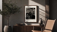 Man carrying pale woman, seated figure poster framed above a fluted sideboard beside an olive tree