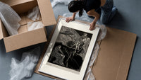 Man carrying pale woman, seated figure framed print being unpacked from protective bubble wrap and a box