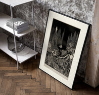 Robed figure atop dark mound poster in a black frame leaning beside a shelf in a raw-plaster loft