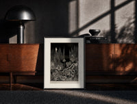Black-framed Robed figure atop dark mound print on a moody console with designer coffee-table books