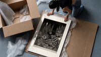 Robed figure atop dark mound framed print being unpacked from protective bubble wrap and a box