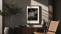 grotesque figures gathered around fantastical scene poster framed above a fluted sideboard beside an olive tree