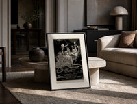 grotesque figures gathered around fantastical scene print in a black frame leaning on a travertine table in a sunlit lounge