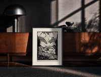 Black-framed Mountain valley landscape with figure print on a moody console with designer coffee-table books