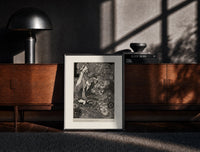 Black-framed Ornate woman with flitting faces print on a moody console with designer coffee-table books