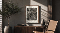 Ornate woman with flitting faces poster framed above a fluted sideboard beside an olive tree