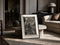Ornate woman with flitting faces print in a black frame leaning on a travertine table in a sunlit lounge