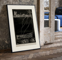 Buried man in coffin underground print in a black frame leaning beside a vintage door on parquet