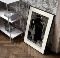 Man walking with torch in dark hall poster in a black frame leaning beside a shelf in a raw-plaster loft