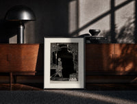 Black-framed Man walking with torch in dark hall print on a moody console with designer coffee-table books