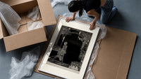 Man walking with torch in dark hall framed print being unpacked from protective bubble wrap and a box