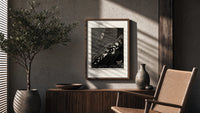 Bound man swarmed by rats poster framed above a fluted sideboard beside an olive tree
