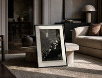 Bound man swarmed by rats print in a black frame leaning on a travertine table in a sunlit lounge