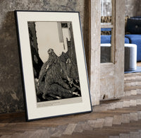 Snarling ape attacking woman print in a black frame leaning beside a vintage door on parquet