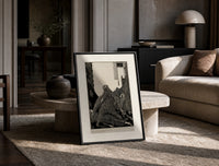 Snarling ape attacking woman print in a black frame leaning on a travertine table in a sunlit lounge