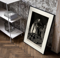 Gaunt sinister man over hidden figure poster in a black frame leaning beside a shelf in a raw-plaster loft