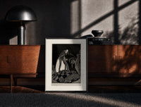 Black-framed Gaunt sinister man over hidden figure print on a moody console with designer coffee-table books