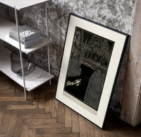 Man dragging woman toward water poster in a black frame leaning beside a shelf in a raw-plaster loft