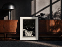 Black-framed Decaying corpse on bed with figures print on a moody console with designer coffee-table books