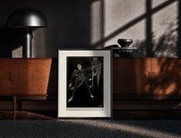 Black-framed Two men in a sword duel print on a moody console with designer coffee-table books