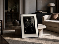 Two men in a sword duel print in a black frame leaning on a travertine table in a sunlit lounge