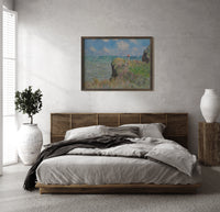 Woman with parasol on cliff print in a dark wood frame above a rattan bed on a plaster wall
