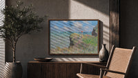 Woman with parasol on cliff print in a wood frame above a fluted sideboard beside an olive tree