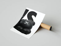 Close-up of a KAWS figure with an X-marked eye resting against bold white typography, rolled print