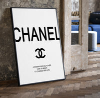 Chanel logo with quote print in a black frame leaning beside a vintage door on parquet