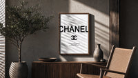 Chanel logo with quote poster framed above a fluted sideboard beside an olive tree