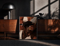 Black-framed Combing Hair with Painted Nails print on the floor in front of a dark wooden console