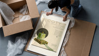 Green perfume bottle on box framed print being unpacked from protective bubble wrap and a box