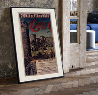 Medieval castle ruins with tower print in a black frame leaning beside a vintage door on parquet