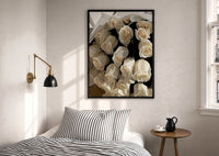 Cream Rose Bouquet print in a black frame above a bed with striped linens, a brass wall lamp and a sunlit window