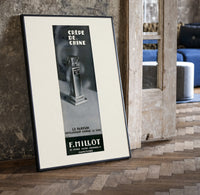Perfume bottle on pedestal print in a black frame leaning beside a vintage door on parquet