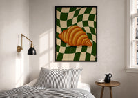 Croissant on Green Checkerboard print in a black frame above a bed with striped linens, a brass wall lamp and a sunlit window