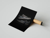 Rolled mocha sneaker print showing metallic lace hardware against a black reflective surface