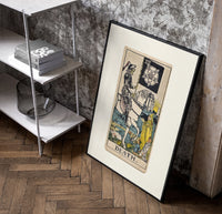 Skeleton knight riding white horse poster in a black frame leaning beside a shelf in a raw-plaster loft