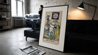 Skeleton knight riding white horse print in a slim black frame leaning on a dark sofa in a concrete print studio