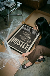 Hands unrolling a black and white Rodman court action print on a smooth concrete floor