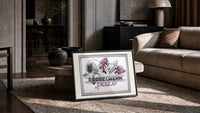 Woman smelling lilac flowers print in a slim black frame leaning on a travertine coffee table