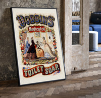 Victorian women in ornate dresses print in a black frame leaning beside a vintage door on parquet