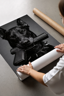 Woman unrolling black and white poster showing Doberman Pistol Spiked Collar artwork on concrete floor with cardboard.
