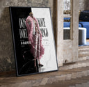 blond man in pink feather coat print in a black frame leaning beside a vintage door on parquet