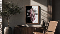 blond man in pink feather coat poster framed above a fluted sideboard beside an olive tree