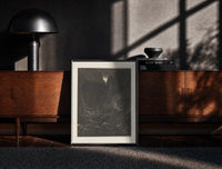 Black-framed Man facing lion in dark forest print on a moody console with designer coffee-table books