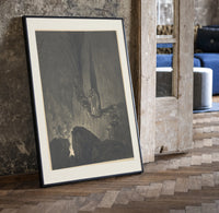 Two robed figures on cliff ledge print in a black frame leaning beside a vintage door on parquet