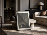 Two robed figures on cliff ledge print in a black frame leaning on a travertine table in a sunlit lounge