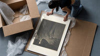 Two robed figures on cliff ledge framed print being unpacked from protective bubble wrap and a box