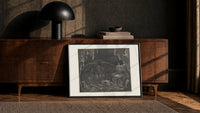Winged demon Lucifer in underworld cavern print in a black frame leaning against a walnut console in lamplight